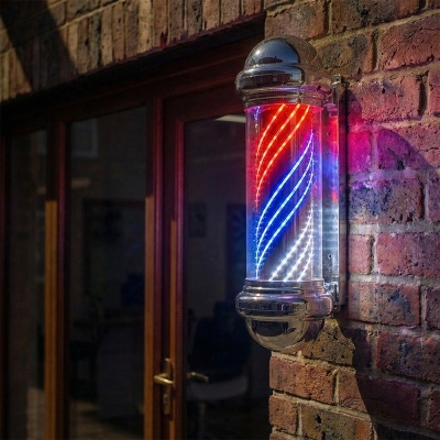 Sinal luminoso de barbeiro colorido montado numa parede de tijolos ao lado de uma porta de vidro