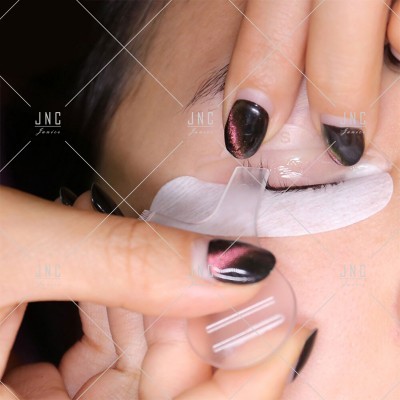 Mãos com unhas pretas a colocar lente de contacto num olho