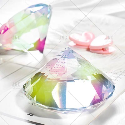 Objeto decorativo facetado transparente colorido sobre papel branco com clips cor-de-rosa em forma de coração