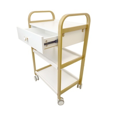 Carrinho móvel branco com estrutura dourada, três prateleiras, gaveta aberta e rodas.