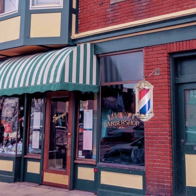 Fachada de barbearia com letreiros e poste tradicional de barbear