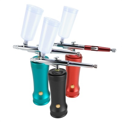 Três aerógrafos com punhos coloridos e copos de plástico