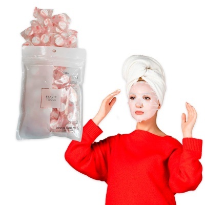 Máscara facial branca em tecido com embalagem transparente e etiqueta 'BEAUTY TOOLS'