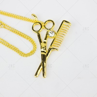 Colar dourado com pendente de tesoura e pente cruzados com pedra brilhante