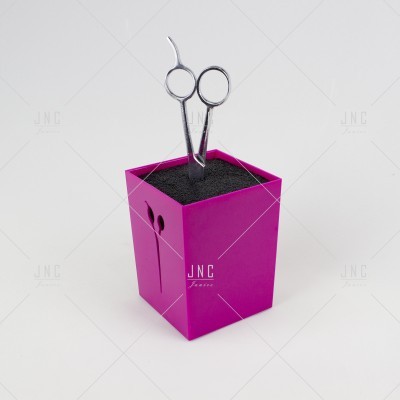 Tesoura metálica prateada em suporte quadrado fúcsia com superfície preta