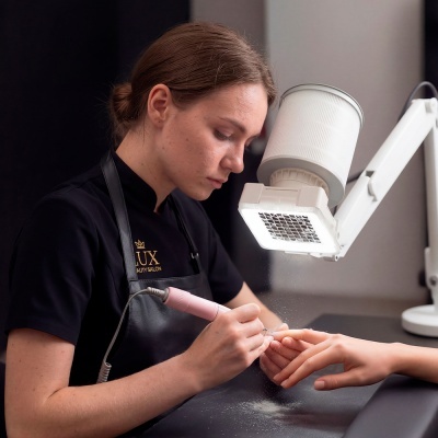 Profissional a fazer manicure elétrica com ferramenta rosa e luz branca