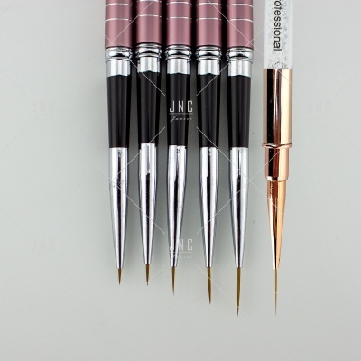 Conjunto de pincéis de maquilhagem finos com cabos rosa e cinza sobre fundo cinzento.