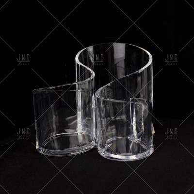 Três vasos transparentes de vidro com formatos irregulares sobre fundo preto