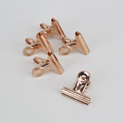 Clipes de metal cobre para papel, cinco unidades sobre fundo branco