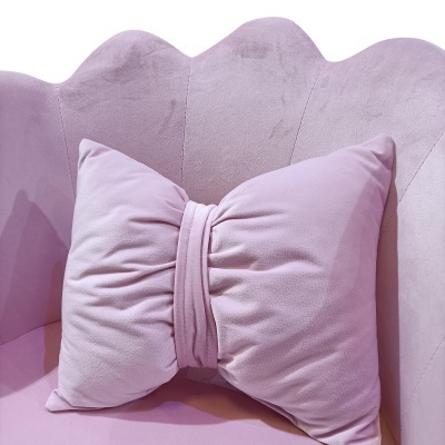 Almofada rosa em forma de laço sobre sofá rosa