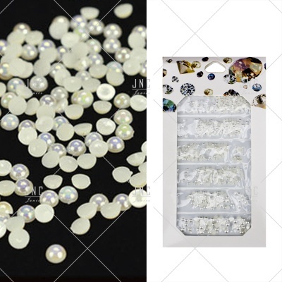 Elementos decorativos pequenos redondos para unhas, branco perolado, em embalagem com estampagem de pedras.