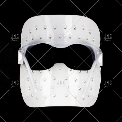 Máscara branca com elementos brilhantes e suporte transparente sobre fundo preto