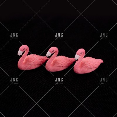 Três figuras decorativas de flamingos rosa sobre fundo preto