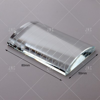 Prisma óptico transparente de vidro com medidas 80mm x 50mm sobre superfície cinza