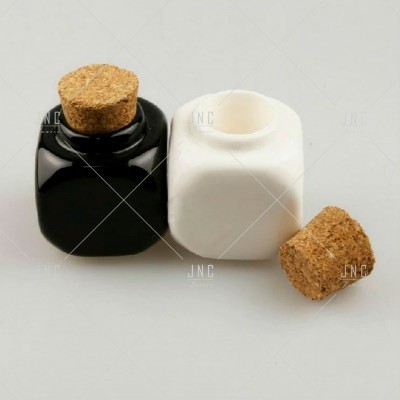 Frascos quadrados preto e branco com tampas de cortiça sobre superfície cinzenta