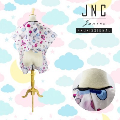 Capa de corte de cabelo infantil branca com bolas coloridas em manequim com fundo decorativo