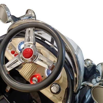 Volante preto e metálico com botão vermelho no centro e painel creme com botões coloridos