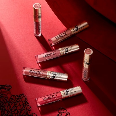 Seis batons líquidos VARIÉTÉ com embalagem dourada e transparente em fundo vermelho