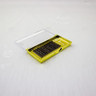 Conjunto de pestanas postiços castanhos numa caixa amarela com tampa transparente