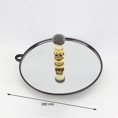 Espelho redondo com moldura preta e pincel de barbear com cabo dourado em formato de caveira