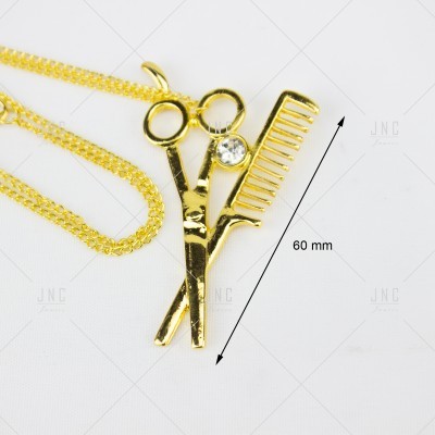 Colar dourado com pendente de tesoura, pente e pedra brilhante em fundo branco.