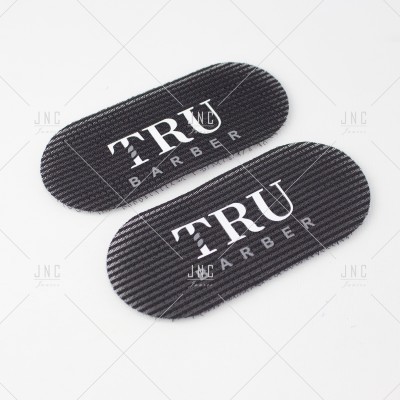 Acessórios pretos ovalados com texto branco TRU BARBER