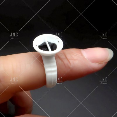 Anel de plástico branco com suporte circular num dedo