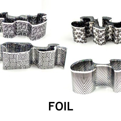 Quatro objetos em forma de laço com padrões geométricos em preto, branco e cinza sobre fundo branco, palavra FOIL abaixo