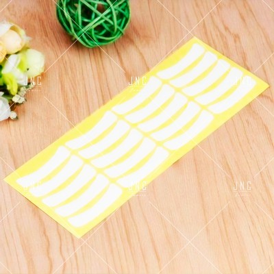 Pacote de adesivos brancos em mesa de madeira com decoração verde e flores