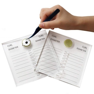 Placas transparentes para medida de diâmetro com etiquetas e círculos coloridos, mão a segurar pinça