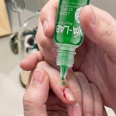 Frasco verde aplicando líquido sobre dedo com ferida sangrante