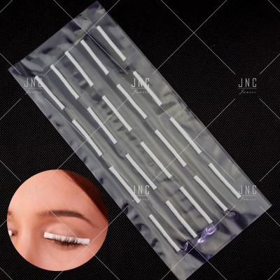 Embalagem transparente com palitos brancos para pestanas sobre fundo preto