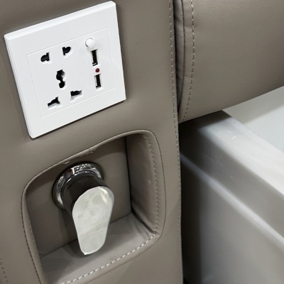 Tomada elétrica branca com USB numa estrutura de couro sintético castanho claro com botão metálico