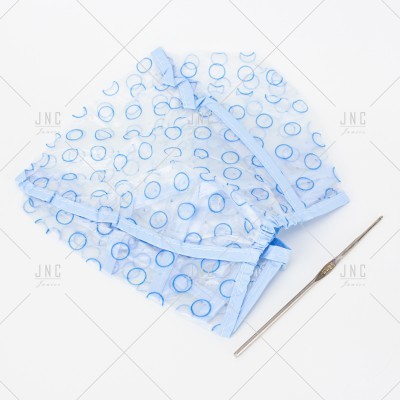 Conjunto de roupa azul claro com padrão de círculos azuis escuros e agulha de crochet prateada