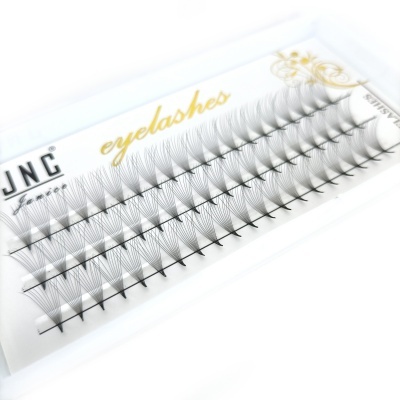 Caixa branca com pestanas postiços agrupados em tufos pretos e texto dourado e preto