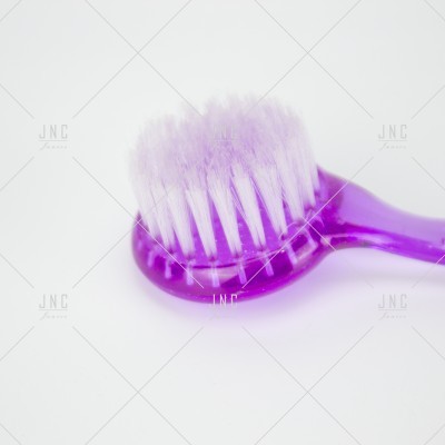 Escova de dentes roxa com cerdas brancas em fundo branco