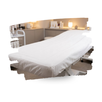 Cama de massagem com lençol branco em ambiente de clínica estética