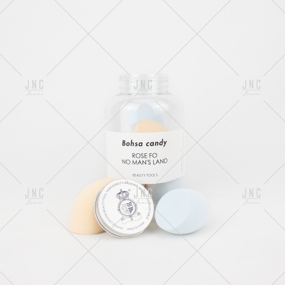 Frasco transparente com esponjas de maquilhagem azul e bege e etiqueta branca