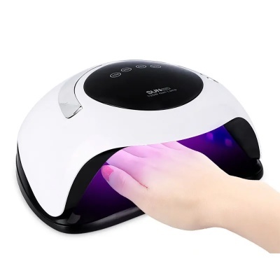 Máquina de secagem de verniz de unhas UV/LED branca e preta com luz roxa e mão a usar