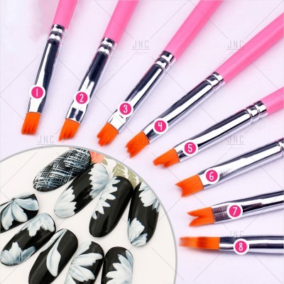 Pincéis de unhas com cabos rosa e cerdas laranja ao lado de unhas decoradas a preto e branco