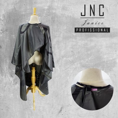 Capa preta para corte de cabelo com padrões cinzentos, pendurada em manequim, texto JNC Janice PROFISSIONAL