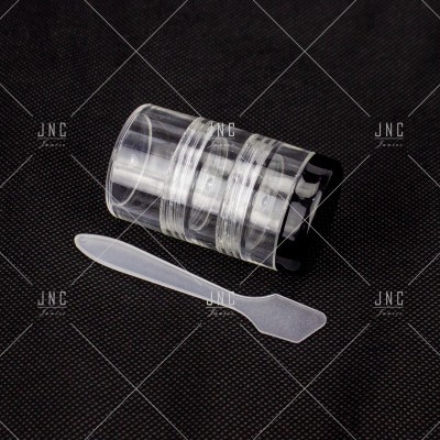 Frasco de plástico transparente com espátula sobre fundo preto