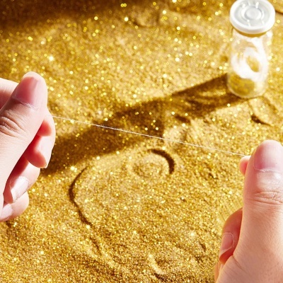 Fio transparente sendo segurado sobre superfície dourada brilhante com frasco ao fundo