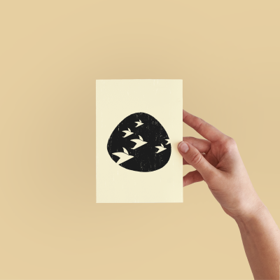 Cartão creme com design preto de pássaros segurado por mão sobre fundo bege