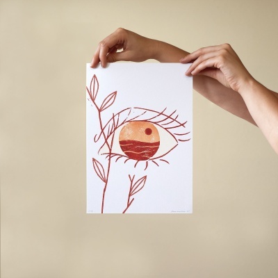 Ilustração de olho estilizado em papel segurada por duas mãos