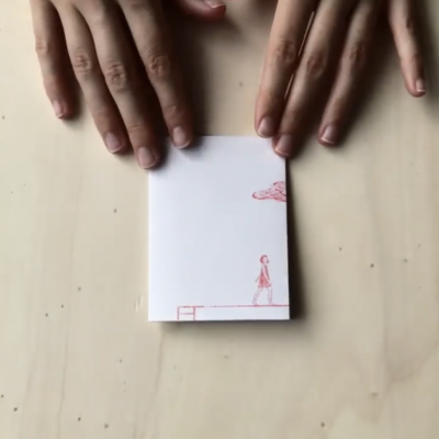 Bloco de notas branco com desenhos vermelhos minimalistas e mãos ao redor