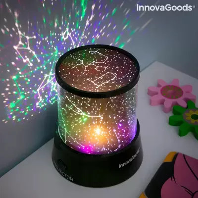 Projetor de constelações iluminado com luzes coloridas sobre mesa branca