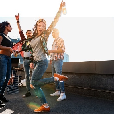 Jovens numa festa ao ar livre num terraço urbano, vestindo roupa casual.
