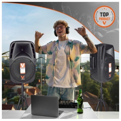 Altifalantes pretos V SOUND em tripés com DJ jovem de auscultadores e mesa branca ao ar livre