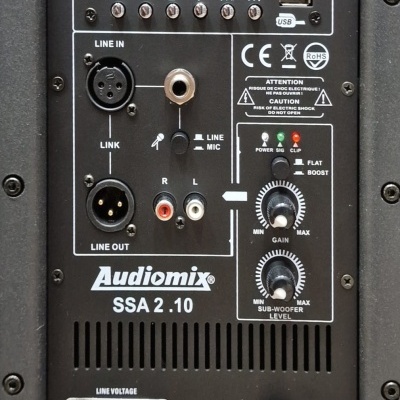 Painel traseiro do sistema de som Audiomix SSA 2.10 com várias entradas e controlos.